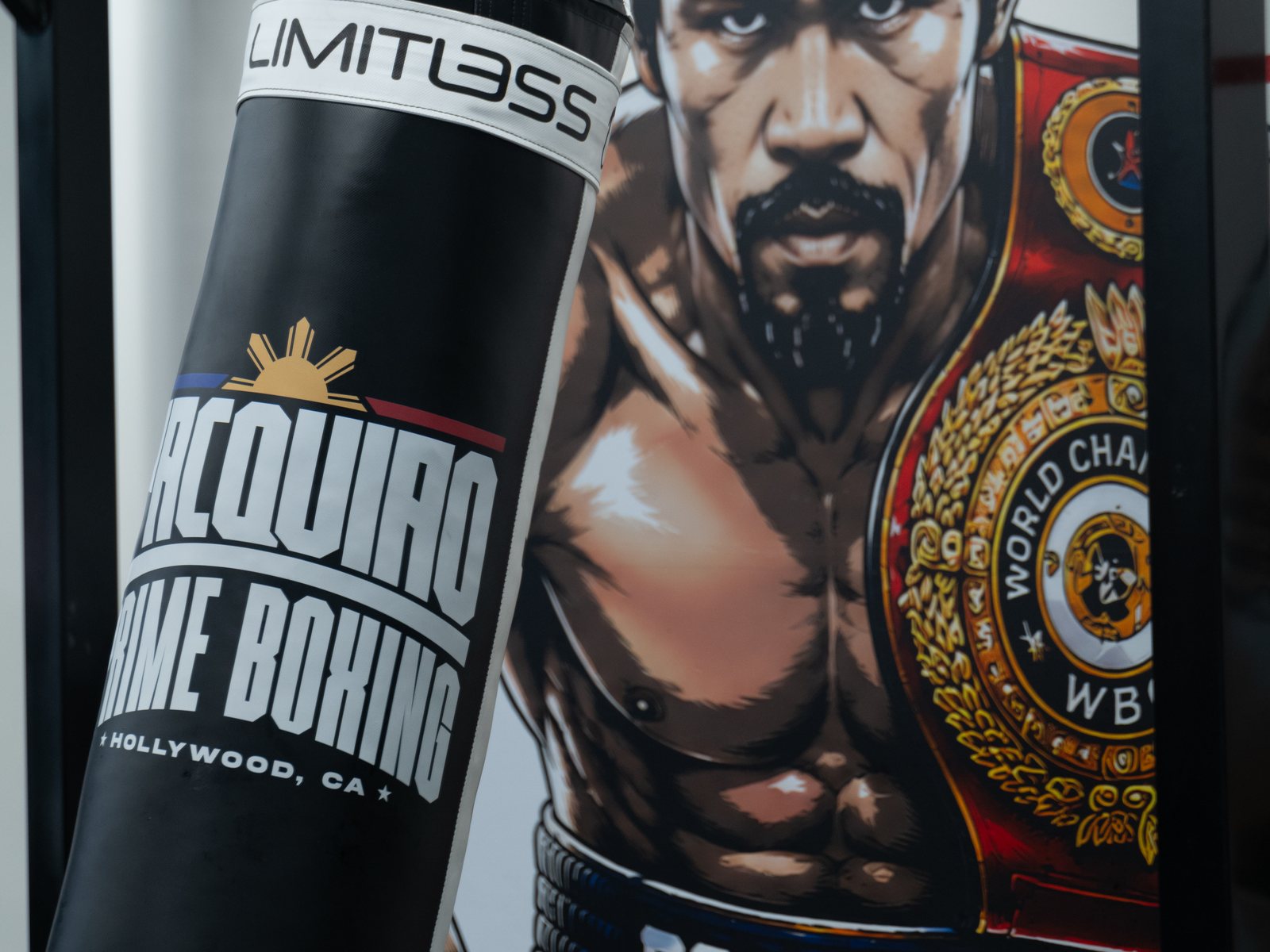 A Pacquiao Prime Boxing heavy bag in front of a mural of Manny
                    Pacquiao holding a world championship belt
