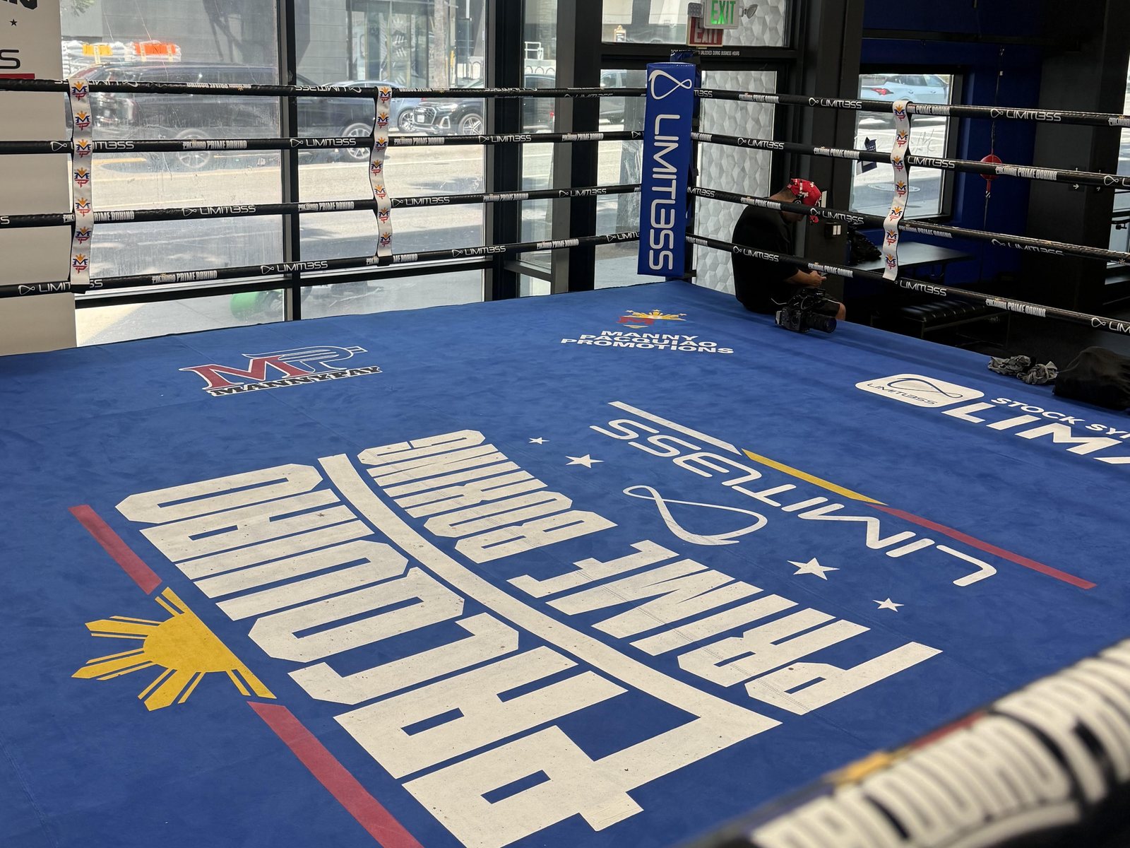The competition ring at Pacquiao Prime Boxing, its canvas carrying the
                    gym's name and the Philippine sun